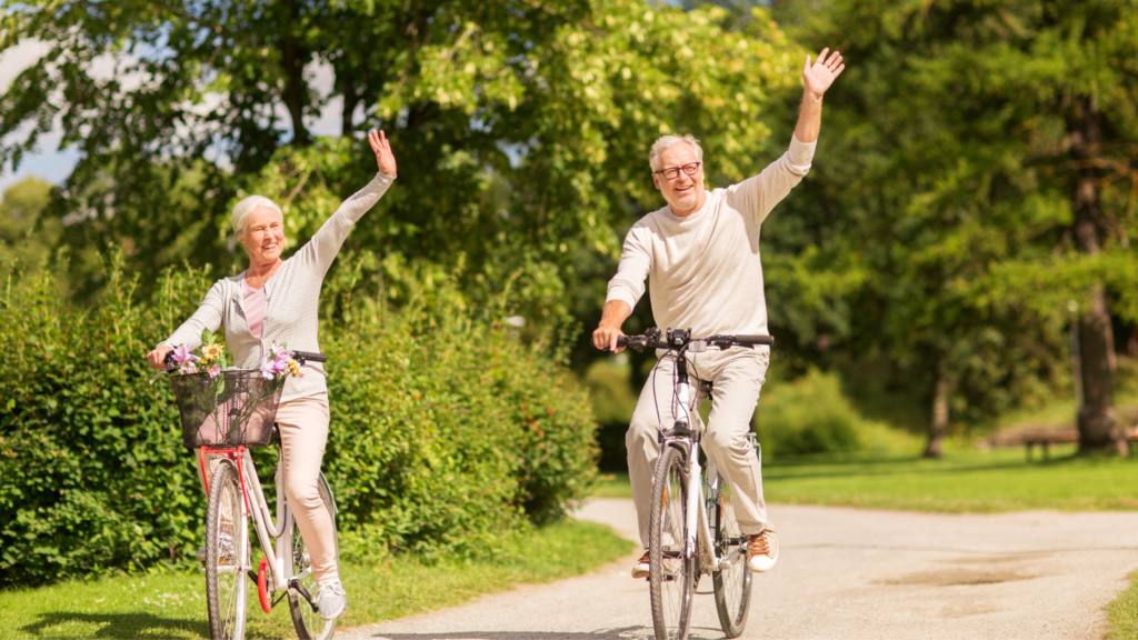 Old couple riding bikes and waving in the bright sunshine